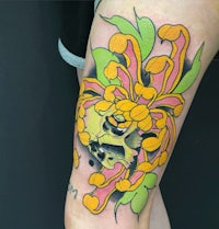 a tattoo with a skull and flowers on the thigh