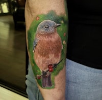 a tattoo of a bluebird sitting on a branch