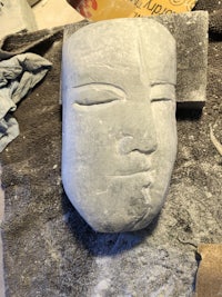 a sculpture of a face is sitting on a piece of cloth