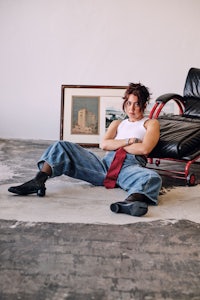 a woman sitting on the floor in jeans and a tie