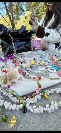a woman is sitting on a blanket with a lot of jewelry on it