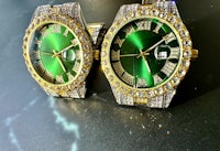 two green and gold watches on a table