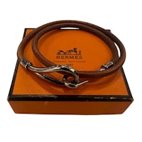 a brown leather bracelet with a silver clasp in an orange box