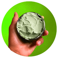 a hand holding a bowl of green whipped cream