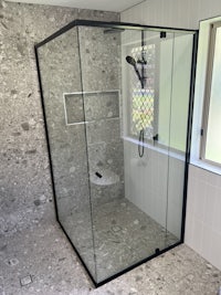 a bathroom with a glass shower stall and tiled floor