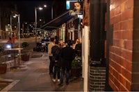 a group of people standing outside a restaurant at night