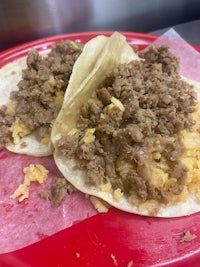 two tacos with meat and cheese on a red plate