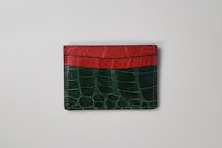a green and red crocodile wallet on a white surface