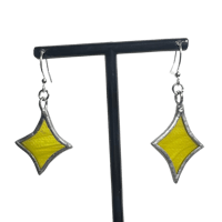 a pair of yellow and silver earrings on a black stand