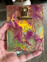 a person holding a clipboard with colorful paint on it