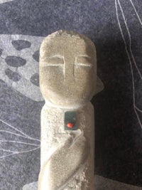 a stone statue with a red bead on it
