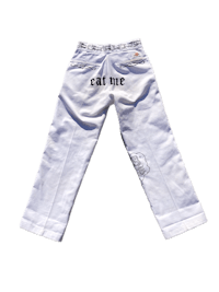 a pair of white pants with the words eat me written on them