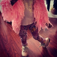 a little girl wearing a pink fur jacket and leggings