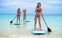 three women stand up paddle boarding in the ocean