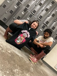 two people posing with a t - shirt in front of lockers