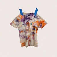 a tie dye t - shirt hanging on a hanger
