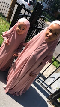 two girls in pink hijabs standing next to each other