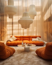 a living room with orange couches and lamps