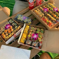 a group of people sitting at a table with boxes of sushi