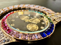a gold watch with multi colored crystals on it