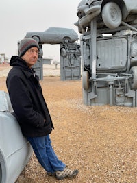 a man leaning against a sculpture of a car