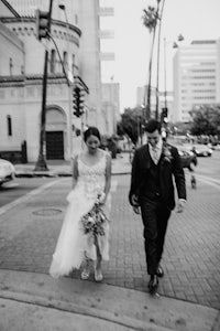 a bride and groom walking down the street in black and white