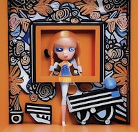 a doll in a box with an orange frame