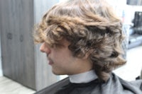 a man with curly hair in a barber shop