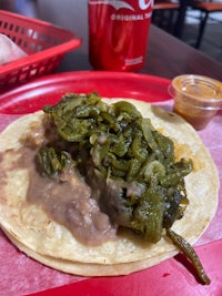 a taco with green peppers on a red tray