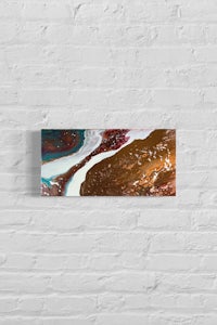 an abstract painting hanging on a brick wall