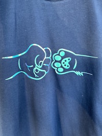 a blue t - shirt with an image of a fist and a paw