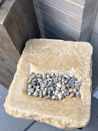 a stone table with rocks on it next to a sidewalk