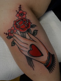 a tattoo of a hand with roses and a heart