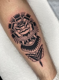 a black and white tattoo of a rose on the forearm