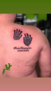 a man's back with a tattoo of a baby's handprints