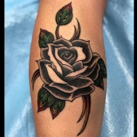a black and white rose tattoo on the forearm