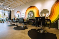 a hair salon with a rainbow mural on the wall