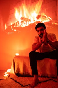 a man sitting on a bed in front of a fire