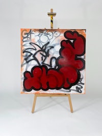 a painting with red and black graffiti on a easel