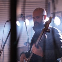 a man with a beard playing a bass in front of a microphone