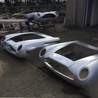 a pair of silver sports cars sitting in a garage