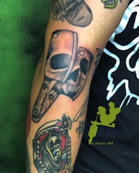 a tattoo of a skull and a skateboard on a man's arm