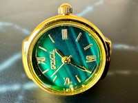 a gold and green watch on a table