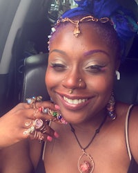 a woman smiling in a car with colorful jewelry on her face