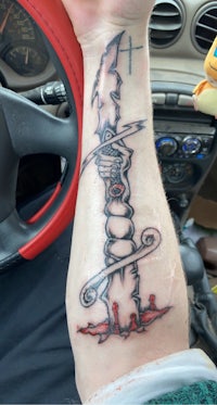a tattoo of a knife on a person's arm