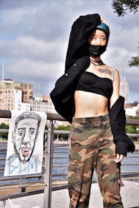 a woman in camouflage pants with a drawing on her face
