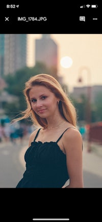 a woman in a black dress is posing in front of a city