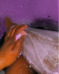 a person in a purple bath tub with soap and bubbles