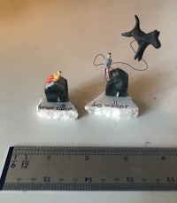 miniature figurines of a dog and a cat on top of a ruler