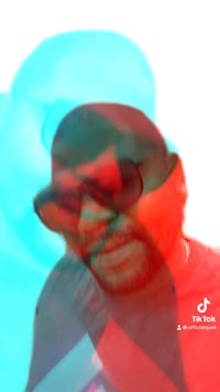 an image of a man with sunglasses and a red and blue background